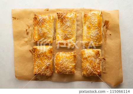Puff pastry dough. Folded baked puff pastry pies portions, top view. Puff pastry dough. Folded baked puff pastry pies portions, top view. 115066114