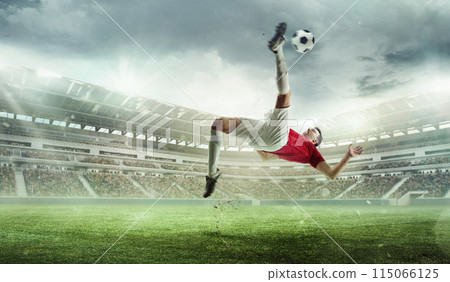 Challenging goal. Man, soccer player in motion during game hitting ball and falling down on grass. Winning match. 3D stadium. Challenging goal. Man, soccer player in motion during game hitting ball and falling down on grass. Winning match. 3D stadium. 115066125