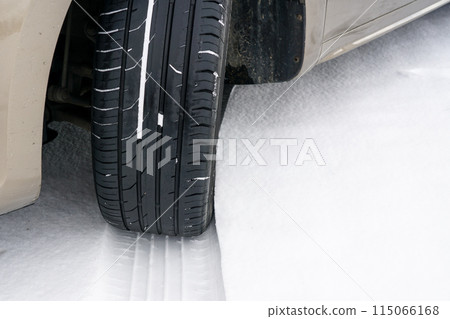 Car wheel with unsafe summer tread tire during driving through slippery snow road at winter season 115066168