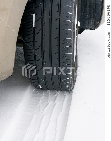Car wheel with unsafe summer tread tire during driving through slippery snow road at winter season 115066169
