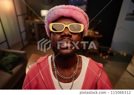 Front view portrait of trendy Black man wearing pink outfit with sunglasses hip-hop style indoors and looking at camera 115066312