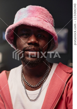 Vertical closeup portrait of African American man wearing pink hip-hop outfit looking at camera with dramatic lighting Vertical closeup portrait of African American man wearing pink hip-hop outfit looking at camera with dramatic lighting 115066340