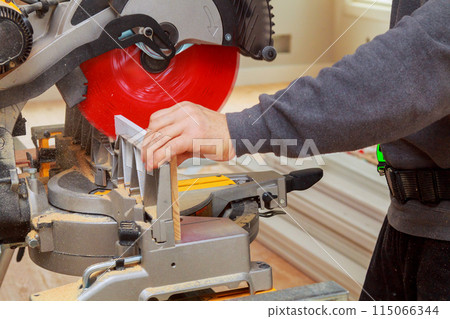 Contractor of using circular saw is cutting wooden moldings on circular saw before installing 115066344