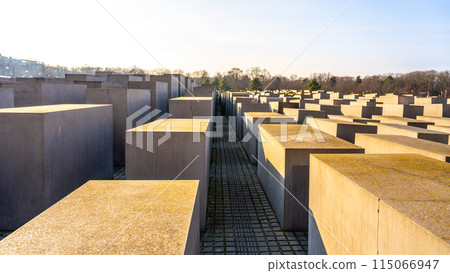 Concrete slabs arranged in a grid form the Holocaust Memorial under the clear sky in Berlin. Germany Concrete slabs arranged in a grid form the Holocaust Memorial under the clear sky in Berlin. Germany 115066947