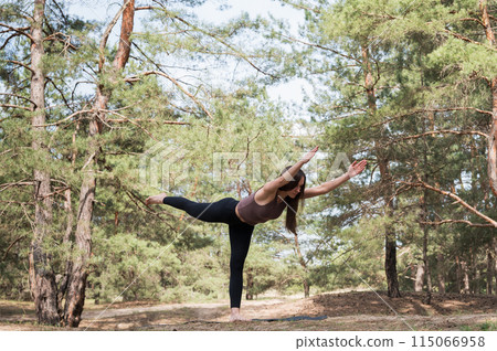 A young attractive woman in sportswear practices yoga in the forest. 115066958