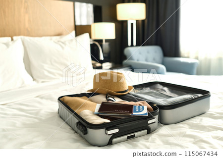 Background image of packed suitcase with passport and tickets on bed ready for travel concept Background image of packed suitcase with passport and tickets on bed ready for travel concept 115067434