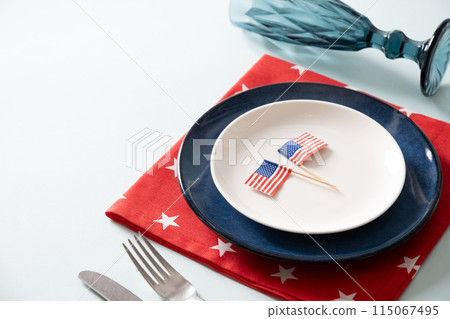 American table setting with USA flags and decoration in national flag colors on blue background. Independence Day. Happy Memorial Day. Close up. Copy space American table setting with USA flags and decoration in national flag colors on blue background. Independence Day. Happy Memorial Day. Close up. Copy space 115067495
