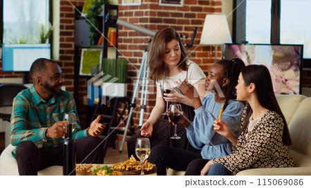 Friends in apartment living room gathered indoors to spend quality time together, eating and drinking. Inclusive group of people socializing at home, gossiping about colleagues Friends in apartment living room gathered indoors to spend quality time together, eating and drinking. Inclusive group of people socializing at home, gossiping about colleagues 115069086