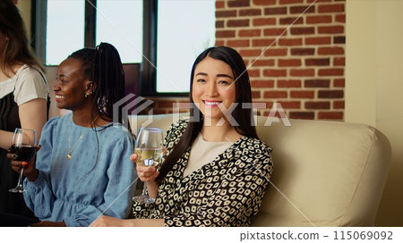 Culturally diverse friends chatting, drinking wine and eating cheese, bread sticks from charcuterie board at home. Multiethnic mates enjoying social life during weekend, spending time with each other Culturally diverse friends chatting, drinking wine and eating cheese, bread sticks from charcuterie board at home. Multiethnic mates enjoying social life during weekend, spending time with each other 115069092