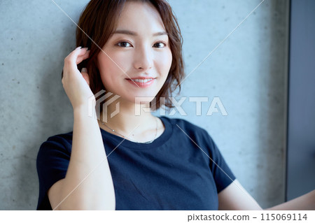 Portrait of a woman standing against a concrete background 115069114