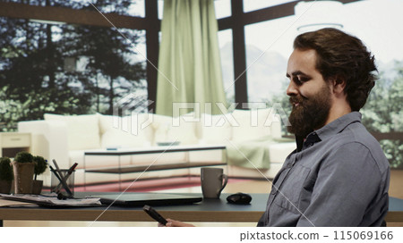 Successful billionaire sitting at his desk in luxury forest villa, relaxed rich person investing money in business. Wealthy person living in a modern cabin in the mountains, browses internet. 115069166