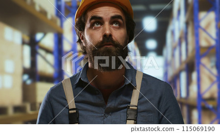 Packaging advisor having merchandise boxes in hands, trying to organize stock and parcels based on delivery time or labels. Warehouse employee preparing to place packages on industrial racks. 115069190