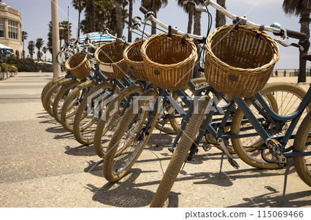 Many Bicycles with Baskets on Beach, Palm Trees and Blue Sky On Background. Bicycle Day. Travel Destination, Vacation. Eco Transportation, Recreation. Horizontal Plane. 115069466