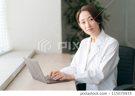 A woman in a white coat examining a patient A woman in a white coat examining a patient 115070935