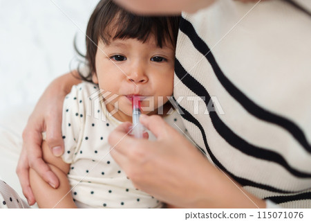 mother feeding liquid medicine to baby girl by syringe. sick toddler 115071076