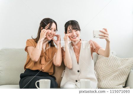 坐在沙發上用智慧型手機自拍的亞洲女性（魯達·哈特） 115071093