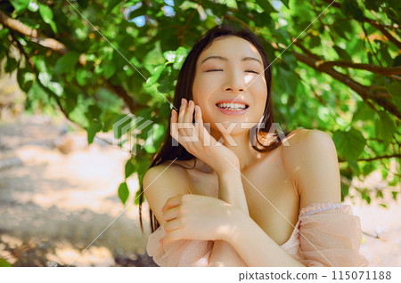 Close up outdoor portrait Beautiful young Chinese Asian woman perfect skin posing outside sunny summer day green foliage. Natural facial treatment. Cosmetology, skin care and spa. Fragnance concept. 115071188