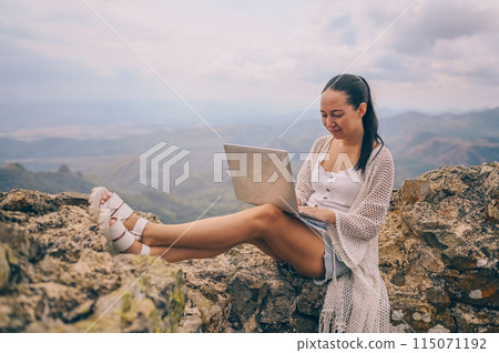 Young woman freelancer traveler working online anywhere outdoors using laptop enjoying mountain peak view. Happy female downshifter holding computer in unusual amazing view workplace at summer. Young woman freelancer traveler working online anywhere outdoors using laptop enjoying mountain peak view. Happy female downshifter holding computer in unusual amazing view workplace at summer. 115071192