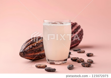 A translucent glass of cacao water, surrounded by raw cacao beans 115072073