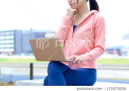 A woman worried about using a computer outdoors in her free time Telework, nomad work, work style reform, cropped, no face 115073026