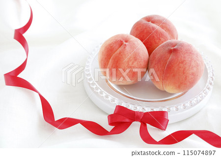 A soft, fluffy white background with peaches and a red ribbon - a gift image 115074897