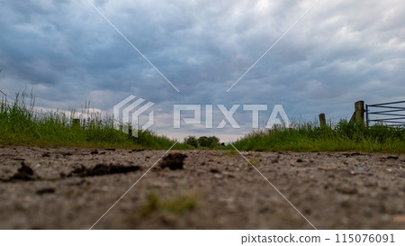 Tranquil countryside road under dramatic cloudy sky, ideal for peaceful journey through nature Tranquil countryside road under dramatic cloudy sky, ideal for peaceful journey through nature 115076091