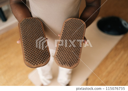 Closeup top view of unrecognizable African man holding in hands wooden Sadhu Board with metal nails standing in living room, preparing to practice. Concept of mindfulness, tranquility, harmony, health Closeup top view of unrecognizable African man holding in hands wooden Sadhu Board with metal nails standing in living room, preparing to practice. Concept of mindfulness, tranquility, harmony, health 115076735