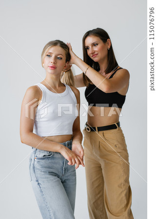 Hair stylist corrects a model's hairstyle on a white background in the studio 115076796