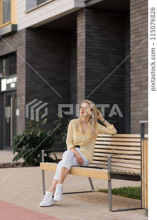Young cheerful stylish woman crouched down to rest while strolling through the city 115076826