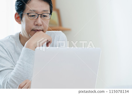 A middle-aged man thinking while looking at a computer 115078134