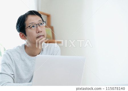 A middle-aged man thinking while looking at a computer 115078140