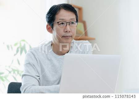 A middle-aged man thinking while looking at a computer 115078143