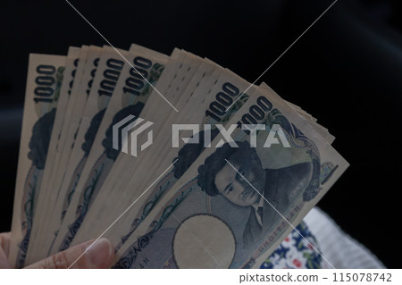 A woman's hands showing a stack of bills spread out on her lap A woman's hands showing a stack of bills spread out on her lap 115078742