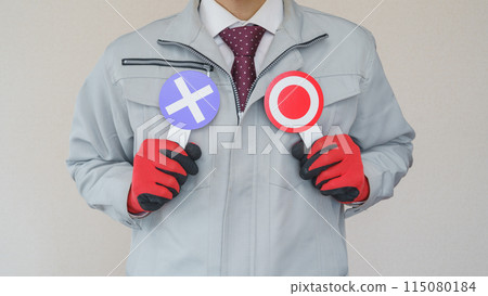 A man in work clothes holding a check mark/cross mark sign | Image of questions and doubts about the construction and manufacturing industries 115080184