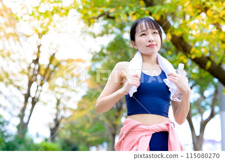 Young woman jogging along a road with roadside trees Diet Bodybuilding Autumn roadside trees Young woman jogging along a road with roadside trees Diet Bodybuilding Autumn roadside trees 115080270