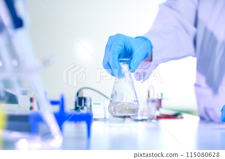 Woman chemist hand in plastic glove shaking laboratory beaker. Scientific Lab for Medicine, Biotechnology Researchers. Woman chemist hand in plastic glove shaking laboratory beaker. Scientific Lab for Medicine, Biotechnology Researchers. 115080628