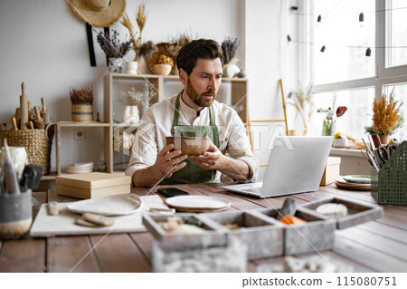 Adult ceramic shop owner using laptop while working in store. 115080751