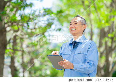 穿著工作服的男人指著平板電腦 115081647
