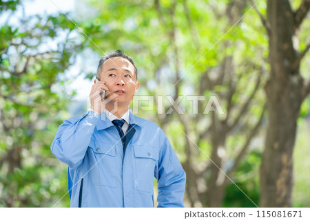 穿著工作服的男人用智慧型手機交談 穿著工作服的男人用智慧型手機交談 115081671