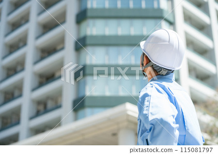 Man in work clothes, office building, looking up 115081797