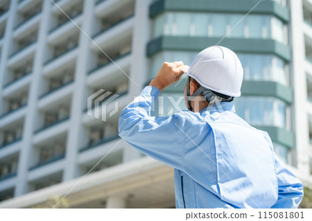 Man in work clothes, office building, looking up 115081801