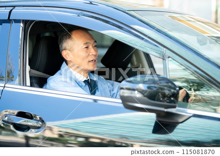 Man in work clothes driving a car Man in work clothes driving a car 115081870