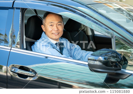 Man in work clothes driving a car 115081880