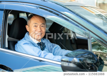 Man in work clothes driving a car 115081888