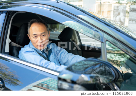 Man in work clothes driving a car 115081903