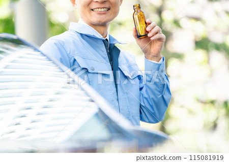 Man in work clothes, outside of car, energy drink, close-up 115081919