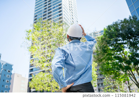 Man in work clothes, office building, looking up Man in work clothes, office building, looking up 115081942