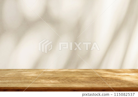 Empty wood table top on beige wall texture with tree leaves shadow background Empty wood table top on beige wall texture with tree leaves shadow background 115082537