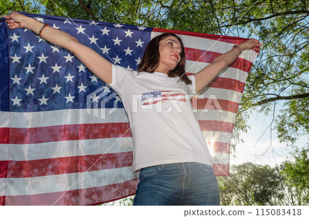 Young woman holding USA flag outdoors at sunset. Independence day. Young woman holding USA flag outdoors at sunset. Independence day. 115083418