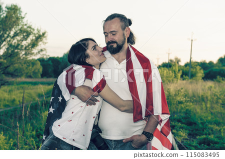 Loving couple celebrating USA Independence Day. Couple in love kissing and holding USA flag 115083495